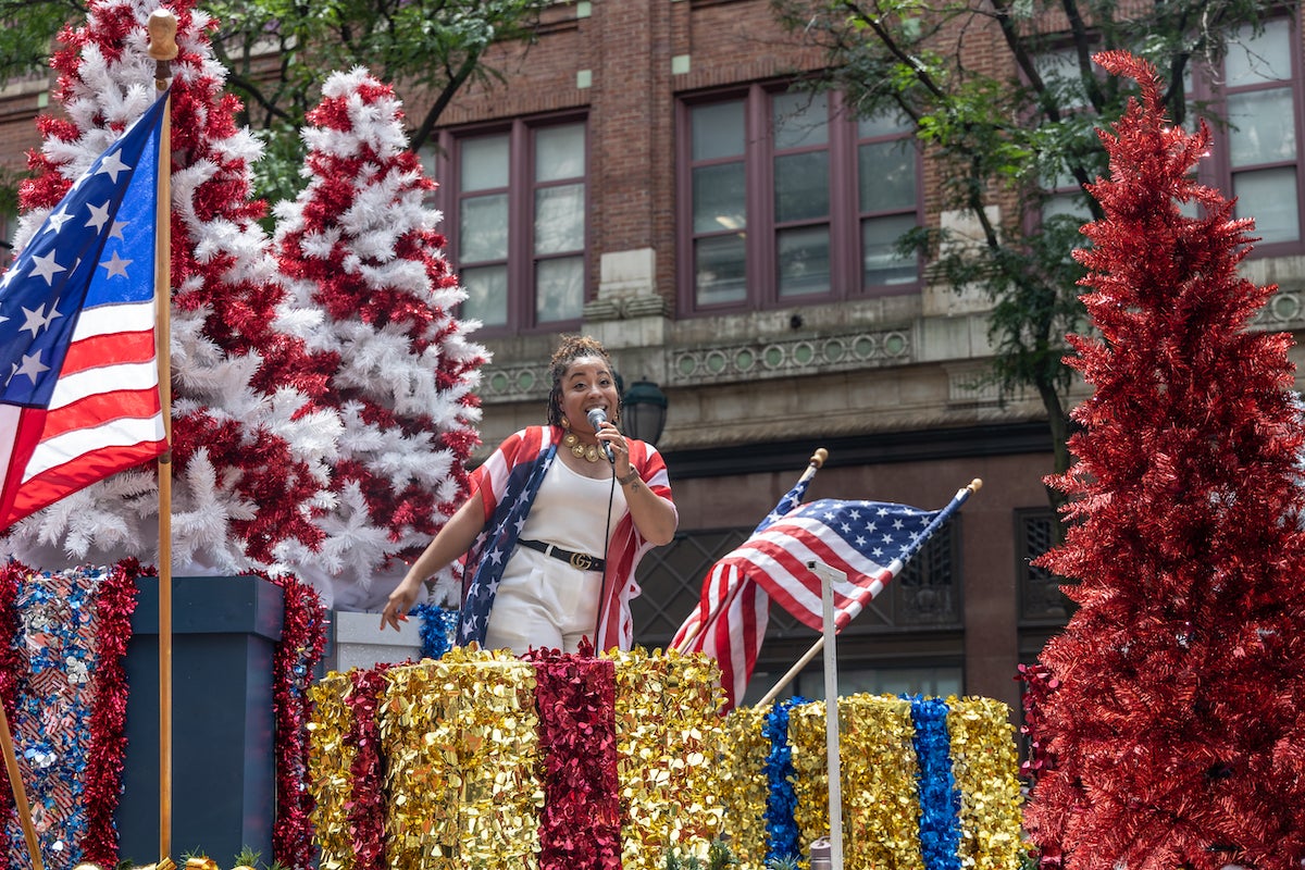 Raquel signs into a microphone on a float.