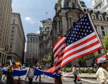 People carry the U.S. flag as they walk by City Hall in the Fourth of July parade.