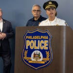 Commissioner Danielle Outlaw speaks at a podium. Mayor Jim Kenney and DA Larry Krasner look on behind her.