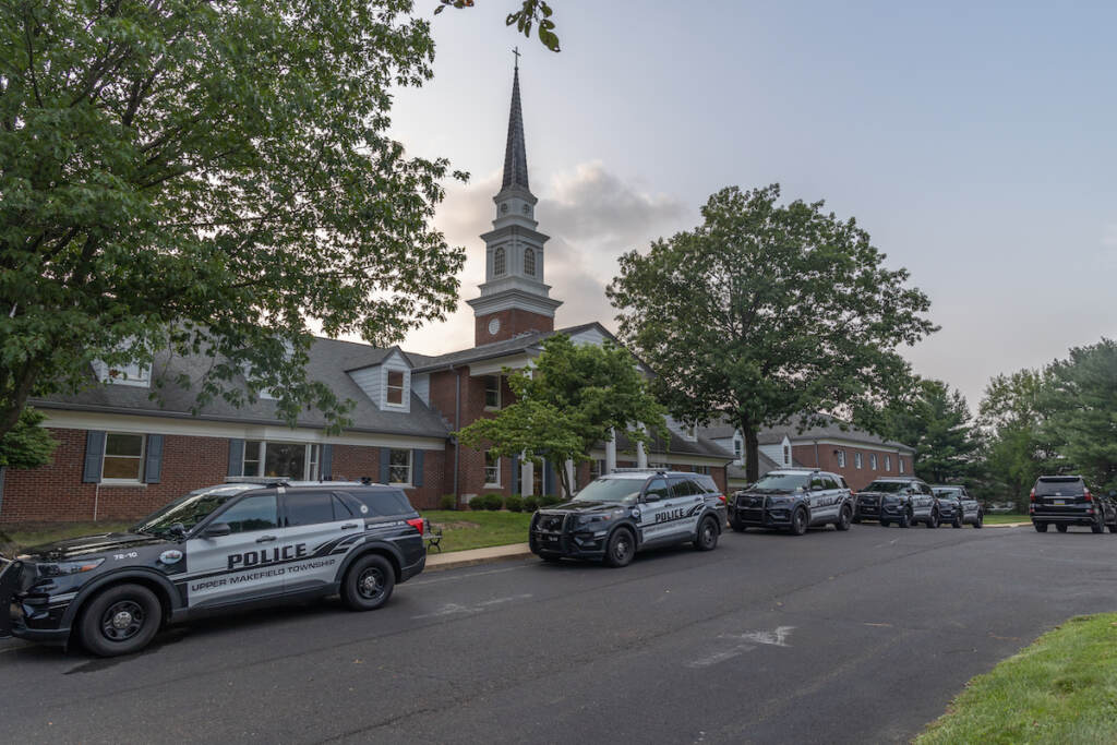 Police cars are parked outside of a church in Upper Makefield Pa.