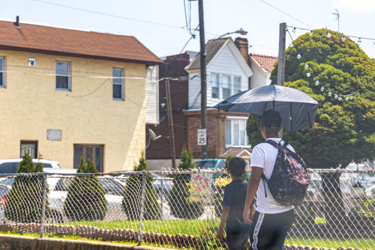 Two kids walk under an umbrella