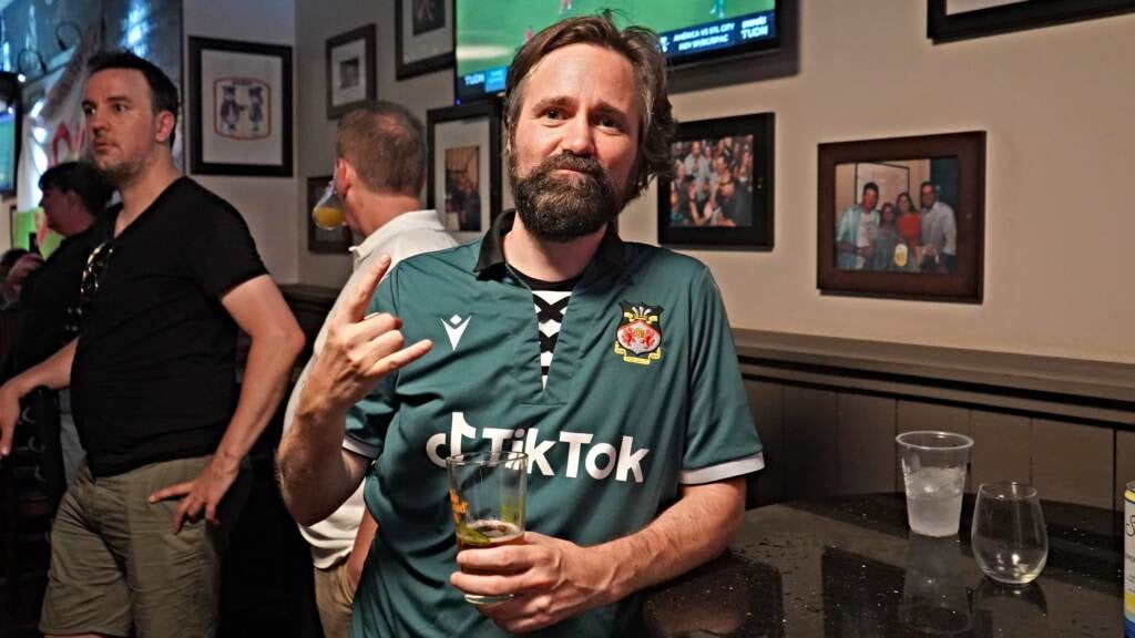 Philadelphia musician Don McCloskey wears an Eagles green Wrexham jersey while holding a drink in Mac's Tavern