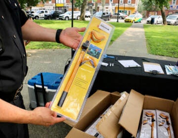 Camden County police officers hand out free steering locks to residents who drive vulnerable Hyundai and Kia cars at Yorkship Square Park in Camden. (Emma Lee/WHYY)