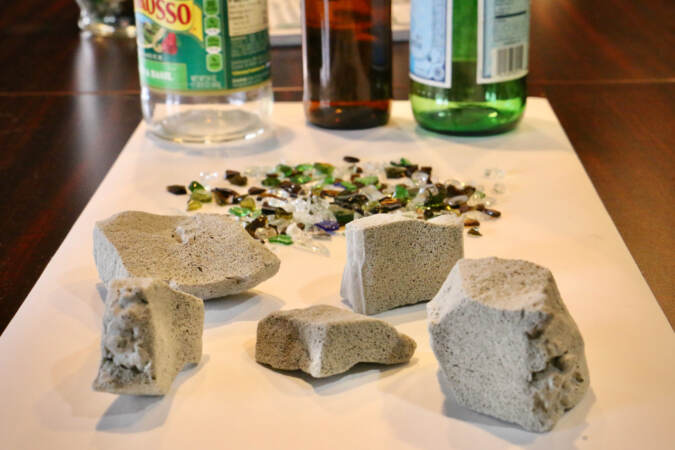 A view of blocks of filling made from crushed glass. Glass bottles are visible in the background.