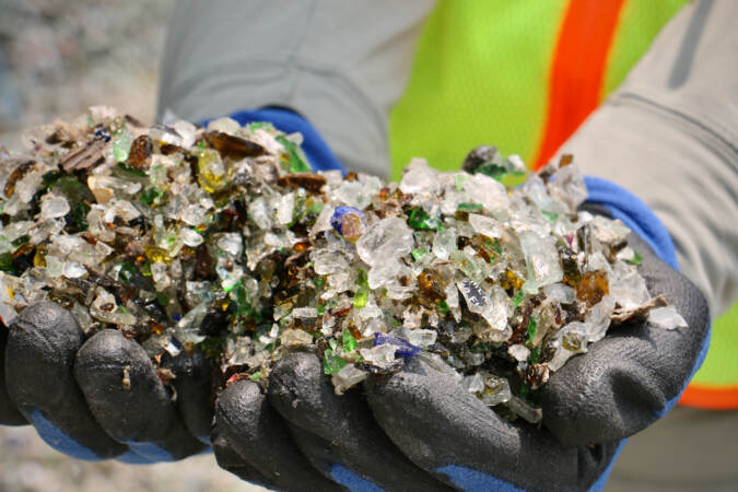 An up-close view of plant manager Ryan Gregor holds handfuls of crushed glass