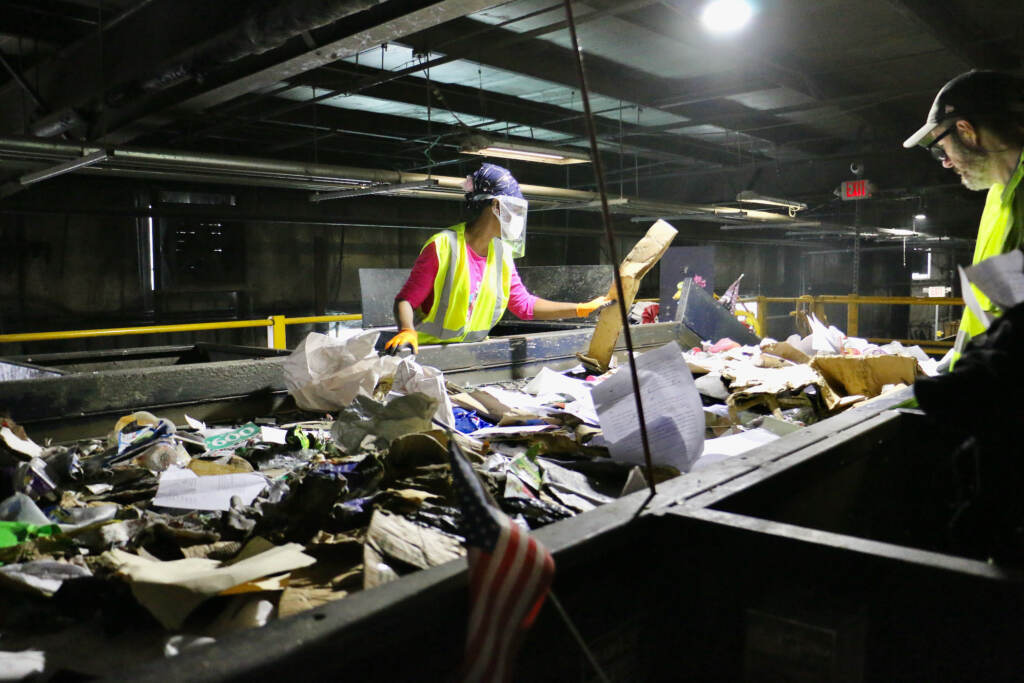 Workers sort plastic, glass, aluminum and paper.