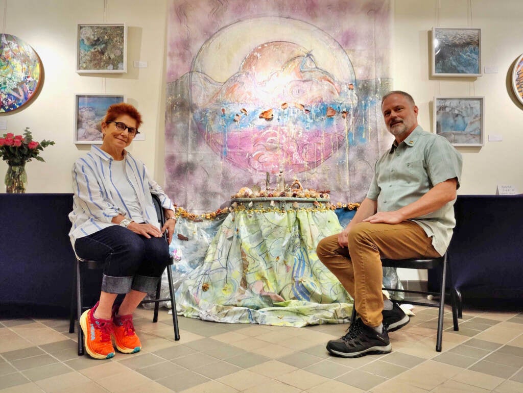 Artist Diane Burko and curator Thom Duffy pose in front of artworks in the new exhibition at Fairmount Water Works.