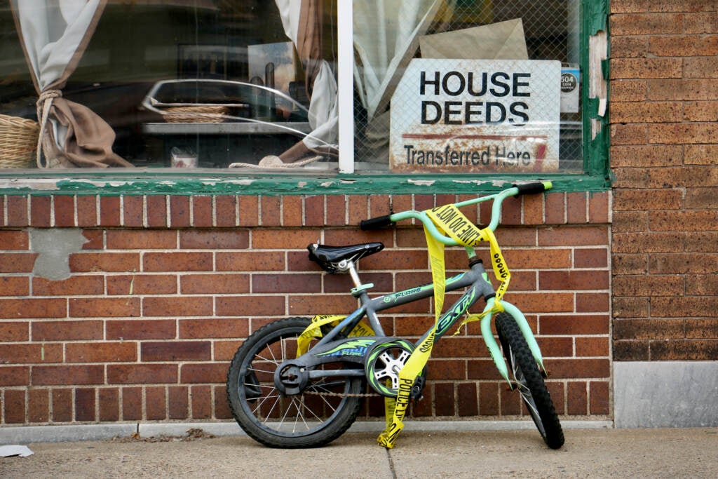 A child's bicycle draped in police tape stands at the corner of 66th Street and Chester Avenue,