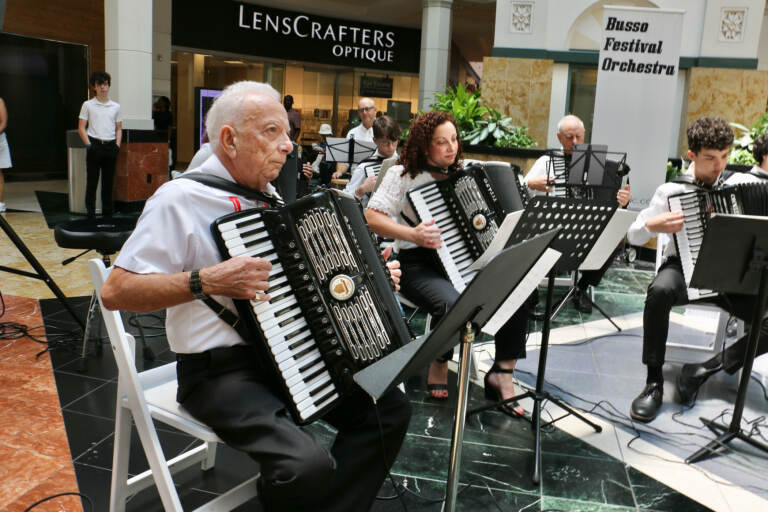Frank Busso Sr. (left), of Woodbridge, Va., raised an accordion playing family, His son, daughter, and grandchildren joined him for a performance at King of Prussia Mall during the annual American Accordionists' Association convention. (Emma Lee/WHYY)
