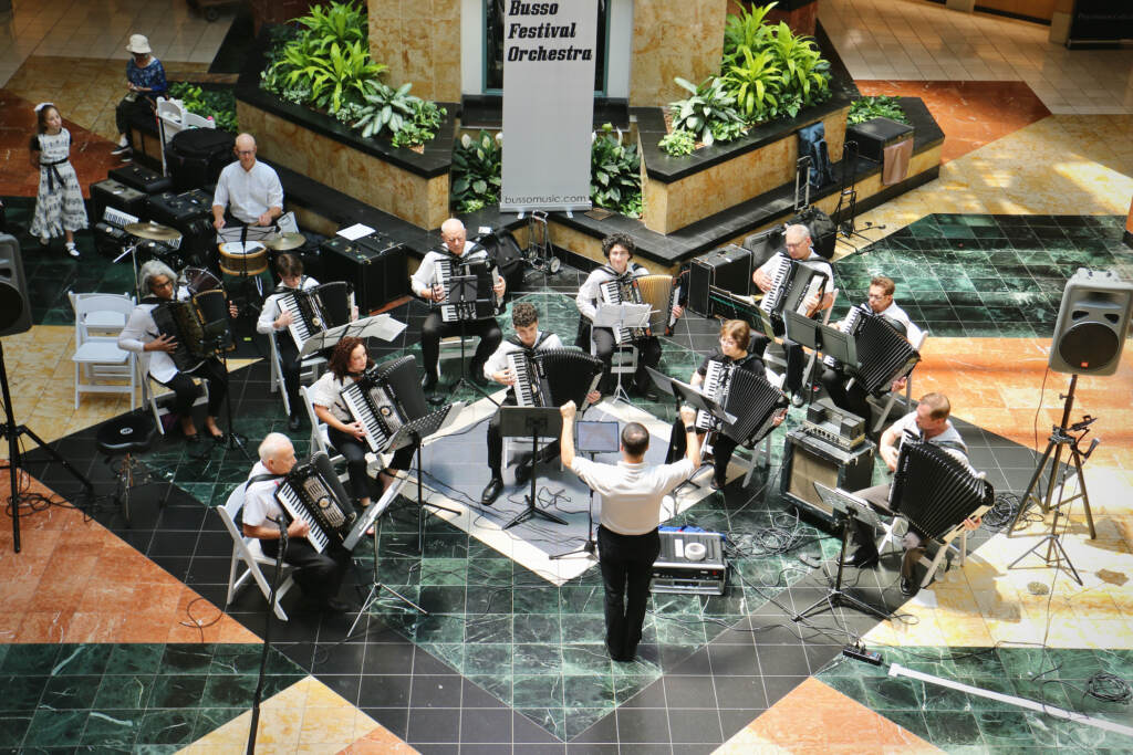 A view from above of accordionists performing in a mall.