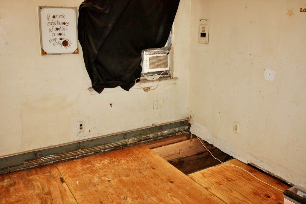 Missing floorboards in a bedroom are visible.