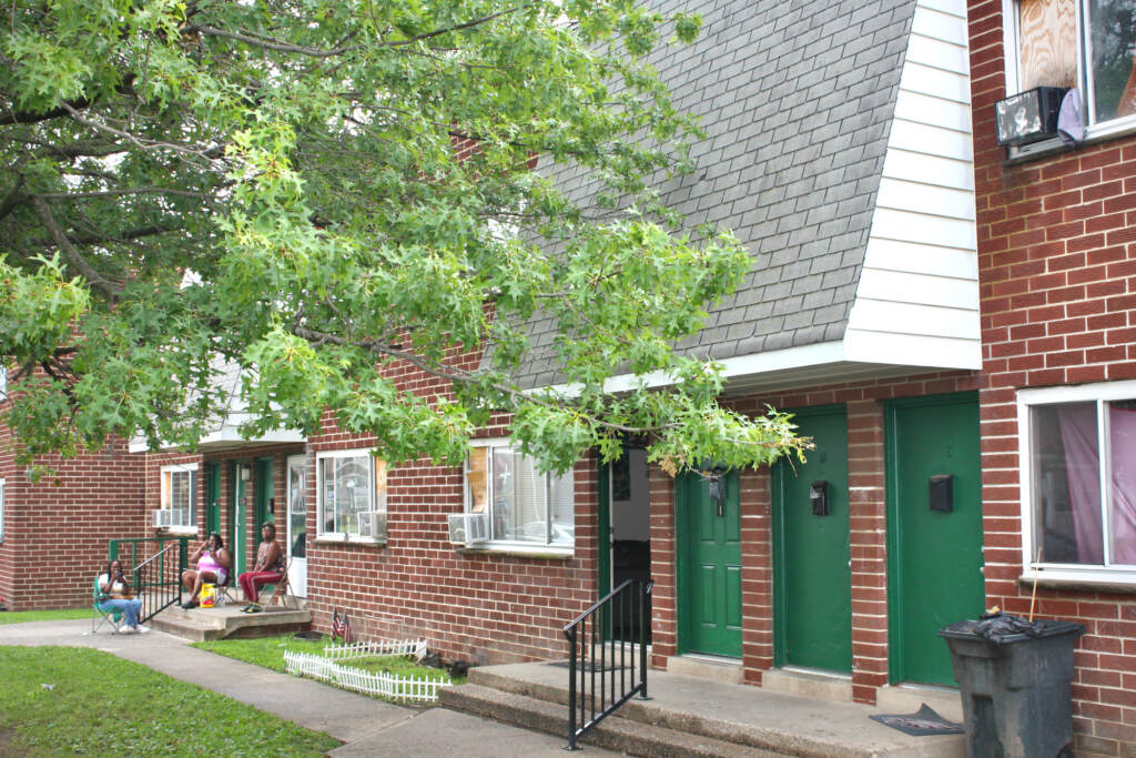 People sit outside on a doorstep of a brick building.