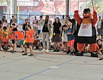 Philadelphia Flyers mascot Gritty cheers on as children send hockey balls into a net in the inaugural snapshot to open the rink