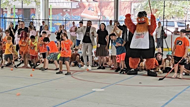 Philadelphia Flyers mascot Gritty cheers on as children send hockey balls into a net in the inaugural snapshot to open the rink