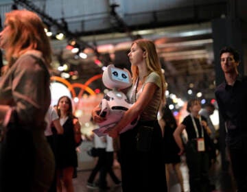 A woman carries a robot during the Vivatech show in Paris, France, Wednesday, June 14, 2023. (AP Photo/Thibault Camus)