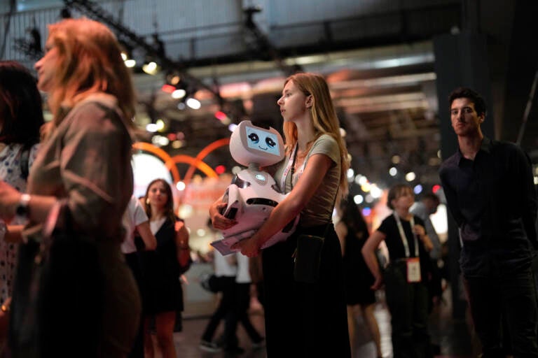 A woman carries a robot during the Vivatech show in Paris, France, Wednesday, June 14, 2023. (AP Photo/Thibault Camus)