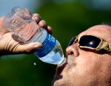 Robert Harris drinks water while taking a break from digging fence post holes, Tuesday, June 27, 2023, in Houston.