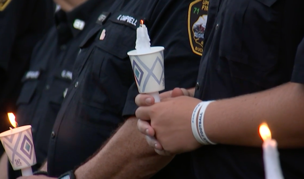 A close-up of first responders holding a candle.
