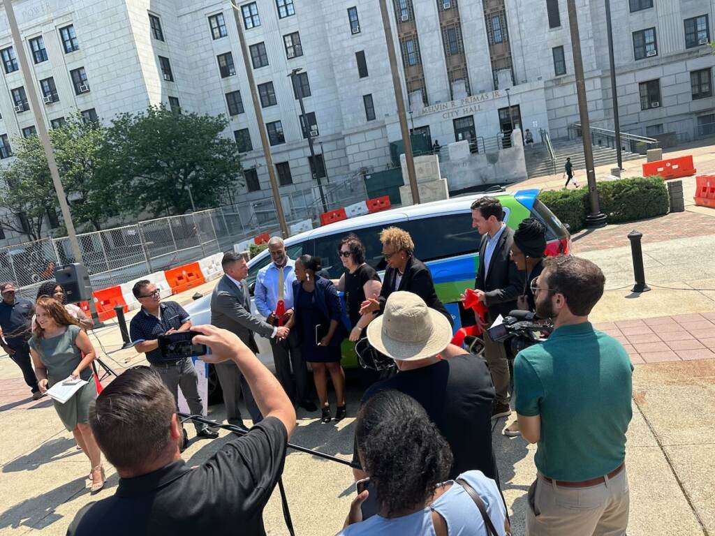 A view from above of Tameeka Mason shaking hands with New Jersey Assemblyman Bill Moen Jr. as people look on. 