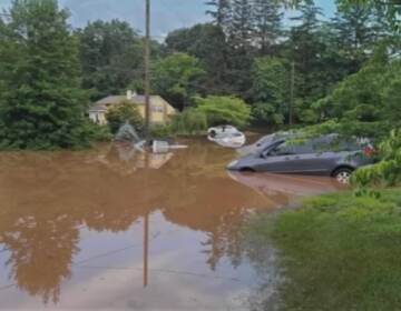 Car is shown in a flooded street.