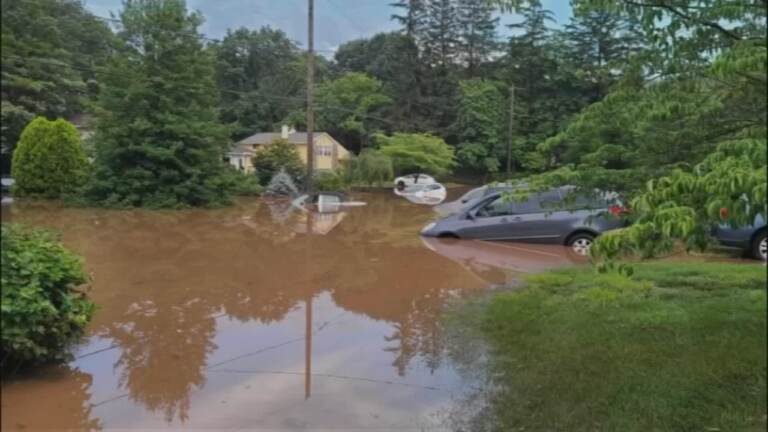 Car is shown in a flooded street.