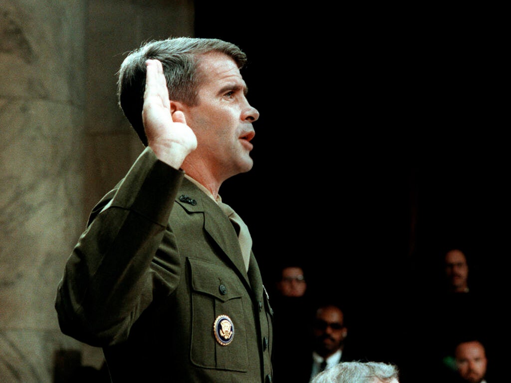 Lieutenant-Colonel Oliver North raises his right hand while taking an oath before Congress.