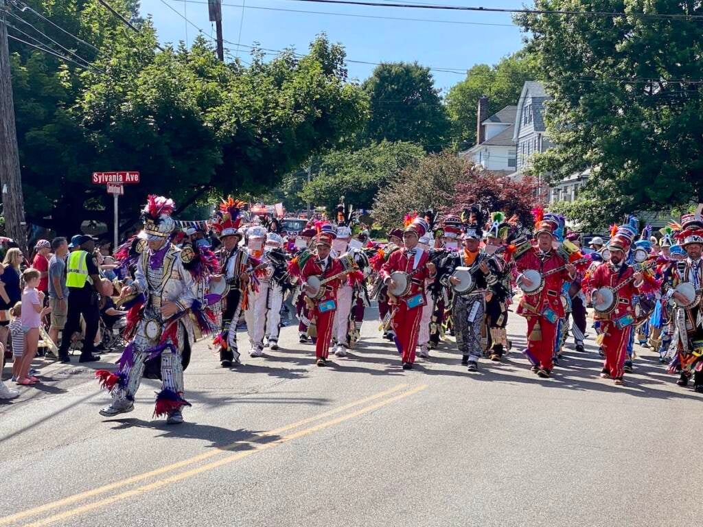 A group of performers walk down a street in the Glenside Fourth of July parade.