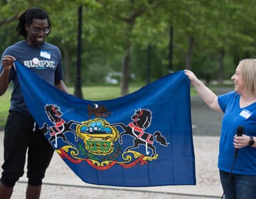 Kofi Osei and Jenn Foster hold a flag together.