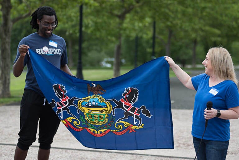 Kofi Osei and Jenn Foster hold a flag together.