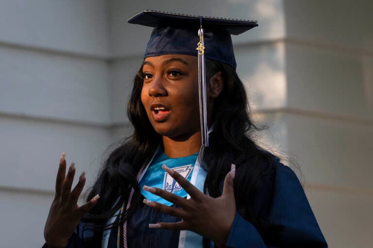 Nylla Miller speaks in a close-up photo. She is wearing her high school graduation cap and gown.