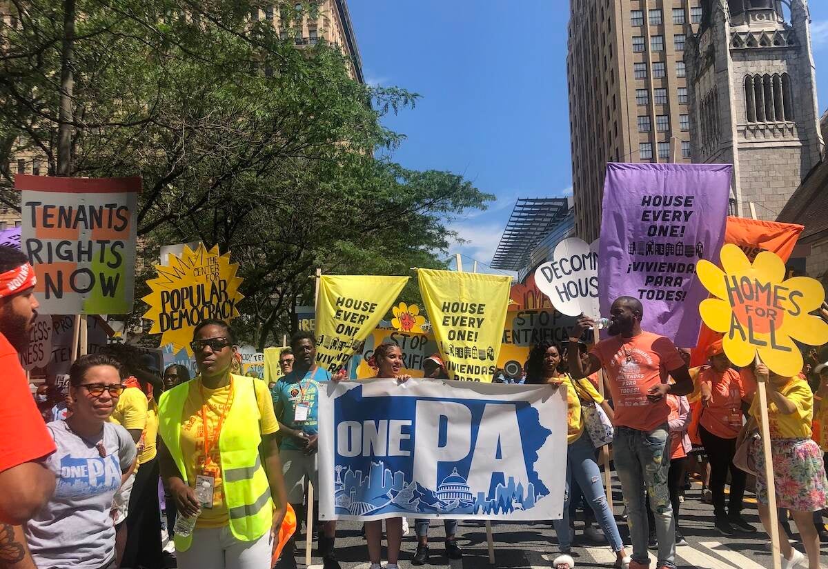 People hold signs as they march, demanding affordable housing for all.