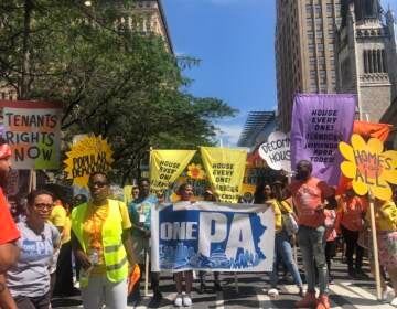 People hold signs as they march, demanding affordable housing for all.