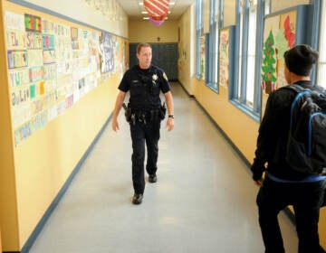 Police officer walks the halls of a high school.