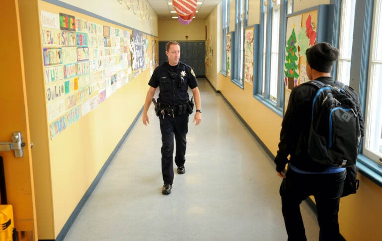 Police officer walks the halls of a high school.