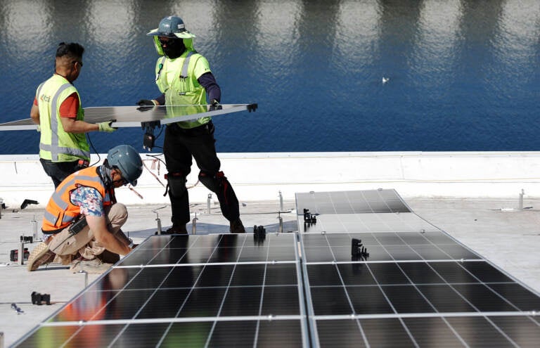 Workers install solar panels at the Port of Los Angeles.