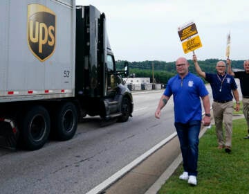 Workers holding up signs next to a UPS truck