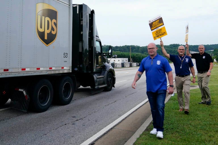 Workers holding up signs next to a UPS truck