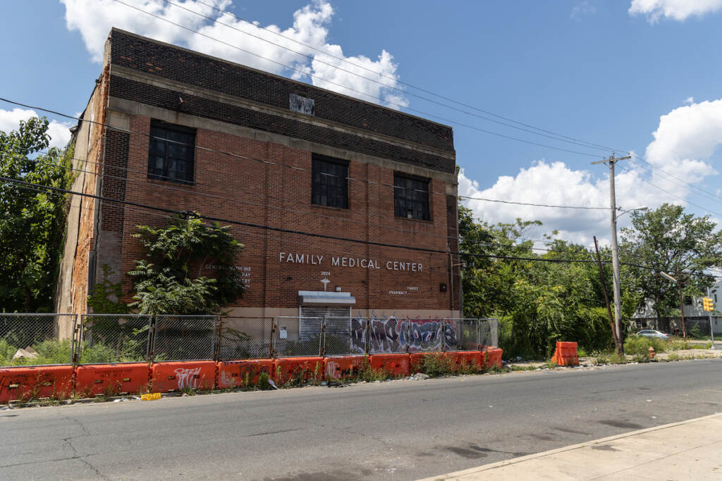 A currently unused brick building labeled "Family Medical Center" is visible on a street, bordered by vacant lots filled with trees.