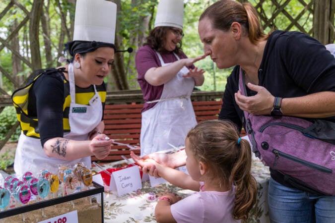 Education program manager Brooke Horowitz (left) gives Lily Landron, 3, a pizza flavored worm