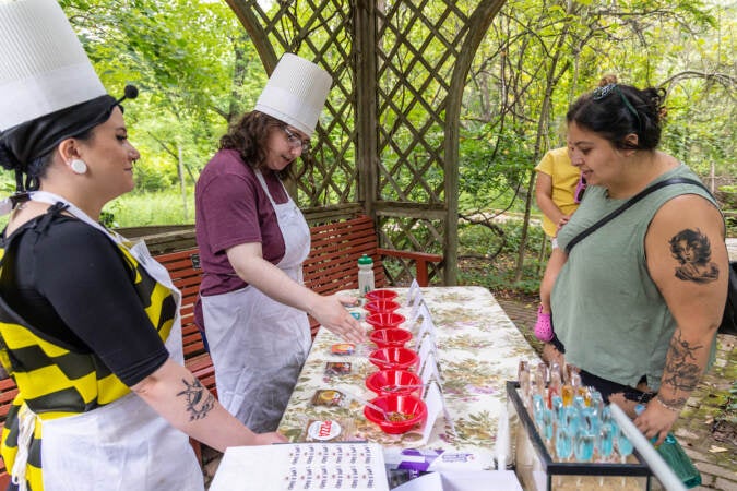 Education program manager Brooke Harowitz (left), volunteer Emily Greco (center) present the Creepy Crawly Cafe’s menu to Julie McName (right)