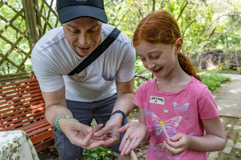 Matt Hoffman and his daughter smile as they hold pizza worms in their hands.