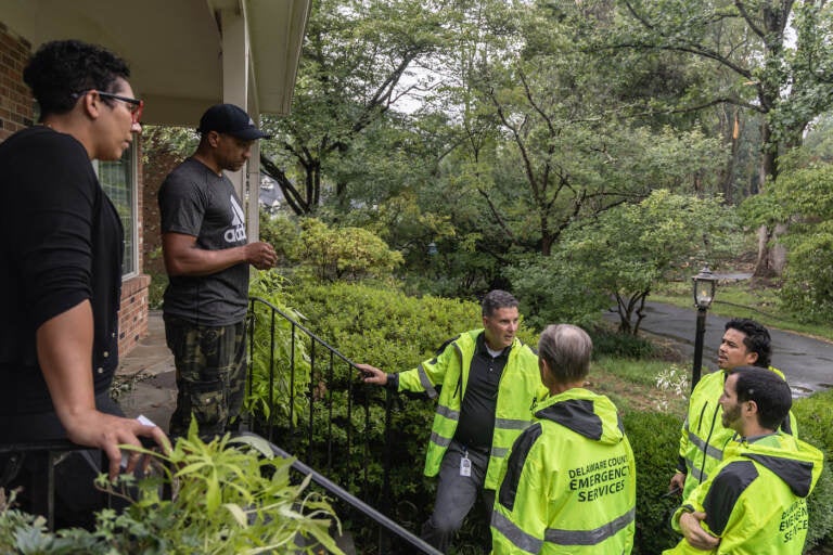 Officials speaking with homeowners after severe storms knocked down trees