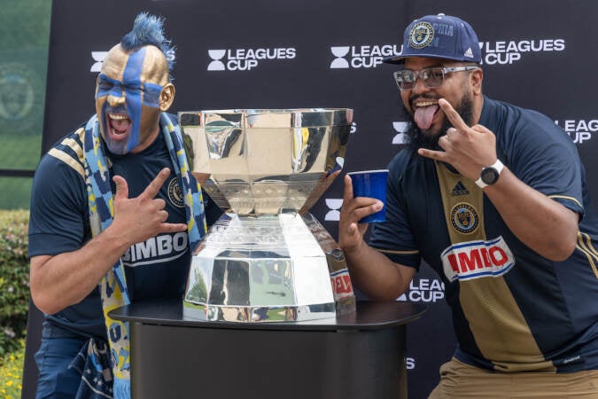 The Philly Sports Guy (left) and Rob Ramirez (right) pose with the Leagues Cup at the Philadelphia Union tailgate before their semi-final match against Inter Miami on August 15, 2023. (Kimberly Paynter/WHYY)