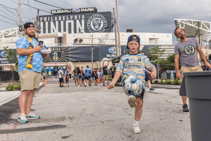 Julian Capps, 9, tries to deliver a soccer ball to a trash can outside Subaru Park at the Philadelphia Union’s pre-game tailgate on August 15, 2023. (Kimberly Paynter/WHYY)