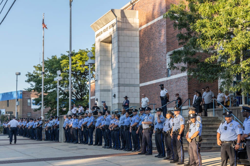 Police officers stand in a row in front of the 24th district headquarters building.