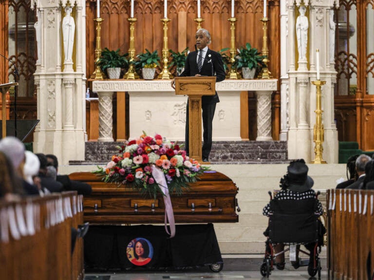 Rev. Al Sharpton at a podium behind Sheila Oliver's casket