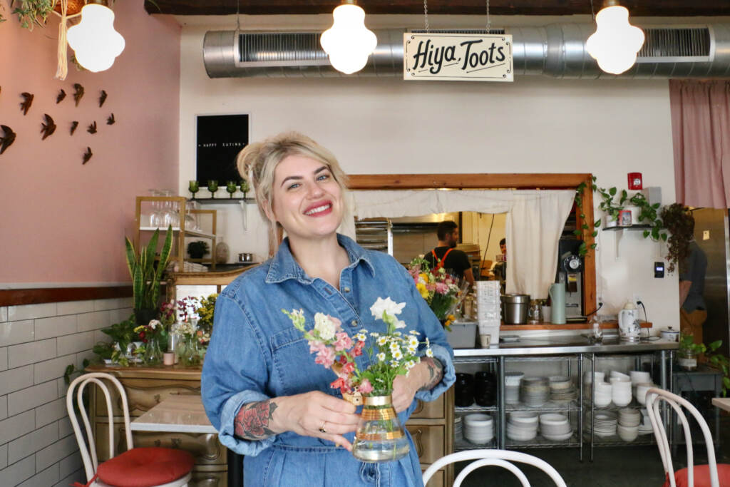 Rachel Klein poses with a vase of flowers in her restaurant.