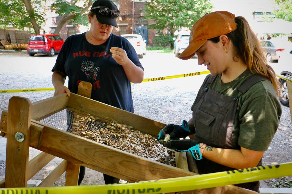 Penn anthropology students Chelsea Cohen and Autumn Melvyn use a sifting board to look for artifacts in gravel.