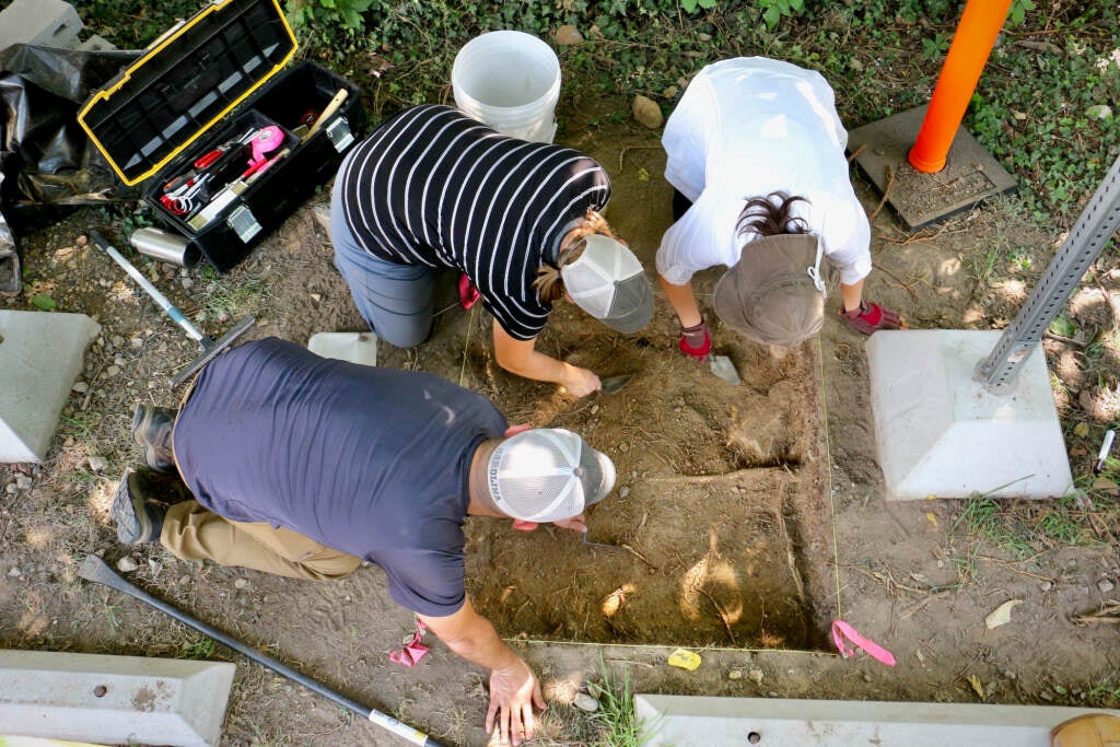 Archaeologists (clockwise from lower left) Doug, Smit, Megan Kassabaum, and Sarah Linn, excavate a meter-square hole