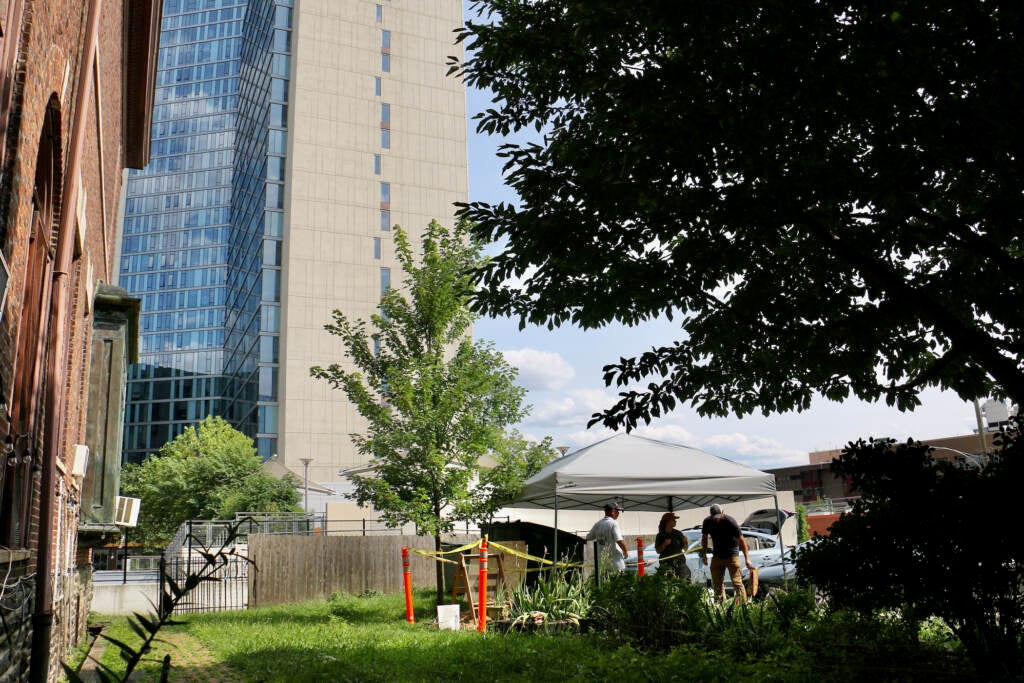 A view from afar of archaeologists working under a tent.